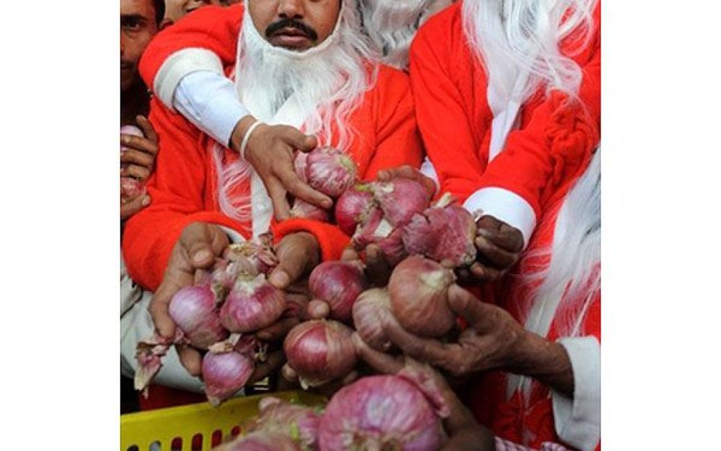 Індія, Амрітсар. Чоловіки у костюмах Санта Клауса роздають безкоштовну цибулю на узбіччі дороги в Амрітсарі. Індійський уряд намагається приборкати зростання цін на основні продукти харчування в країні. / © AFP