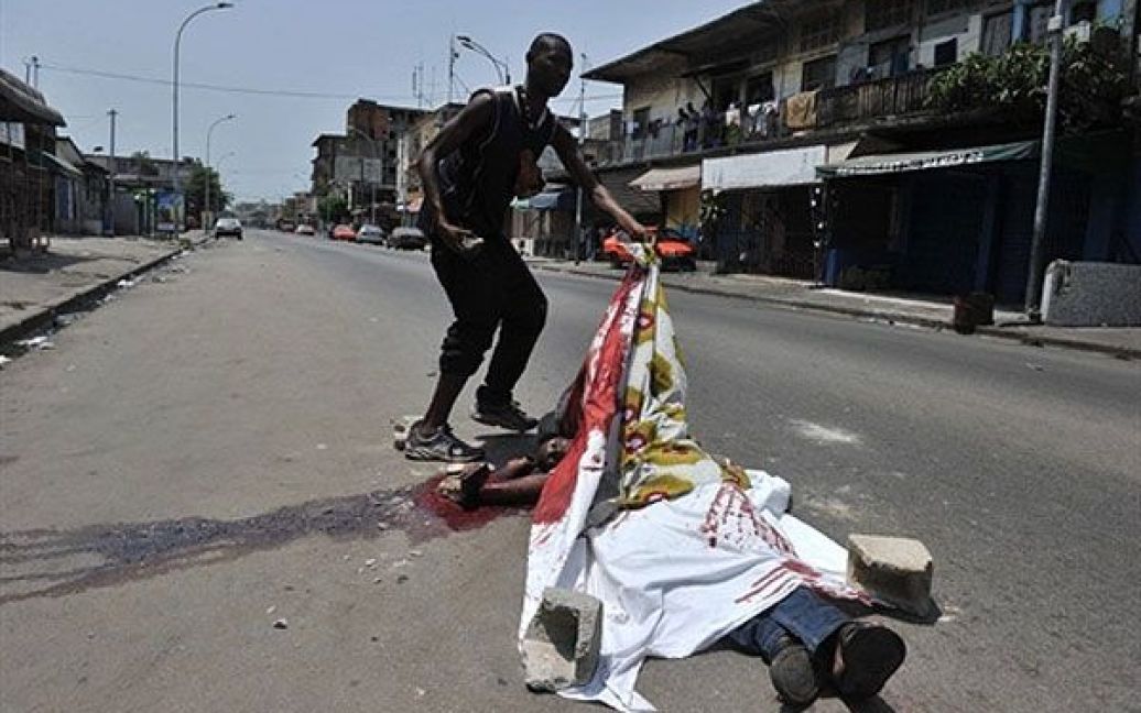 Кот-д&#039;Івуар, Абіджан. Чоловік показує тіло людини, яка була убита під час зіткнень між прихильниками Лорана Гбагбо і його суперника Алассана Уаттара. / © AFP