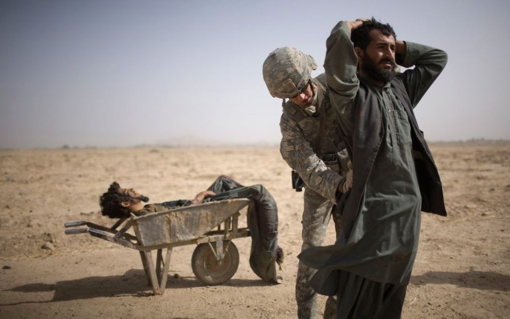 Американський солдат обшукує помічника таліба, чиє тіло лежить у тачці, провінція Кандагар. (AP Photo / Rodrigo Abd) / © The Boston Globe
