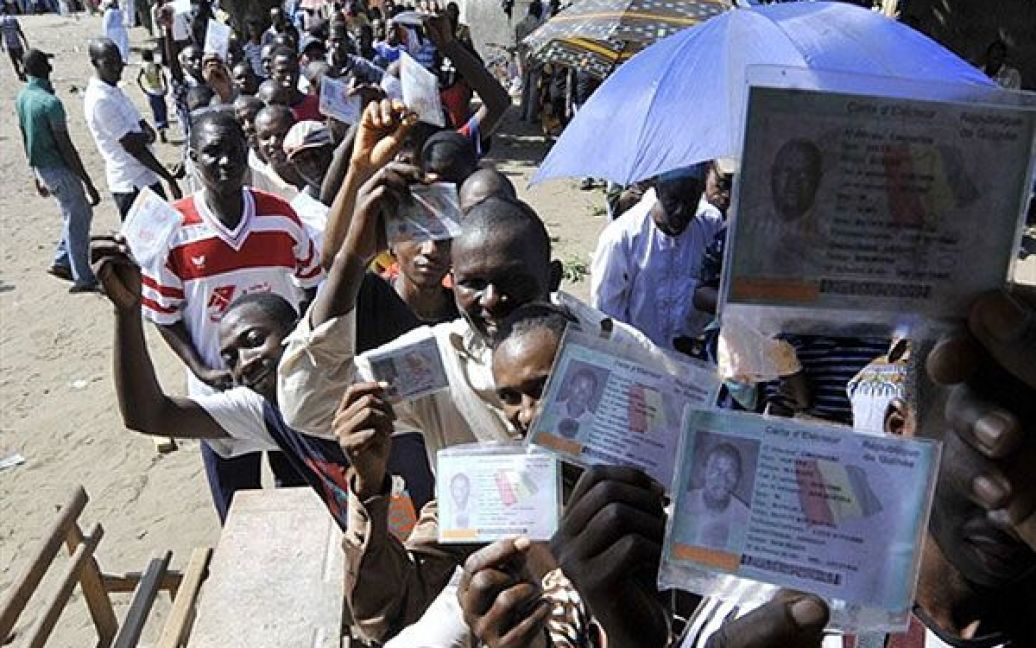 Кот-д&#039;Івуар, Абіджан. Гвінейські жителі Кот-д&#039;Івуара показують свої виборчі карти, доки вони стоять у черзі на виборчу дільницю в Абіджані. / © AFP