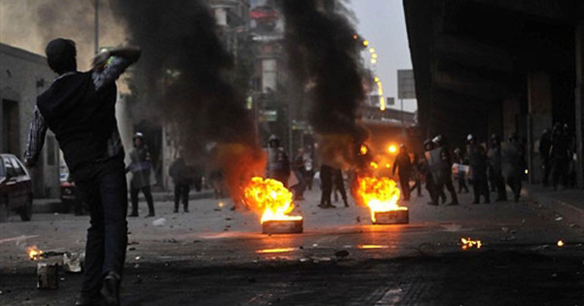 Єгипет, Каїр. Єгипетський ОМОН стоїть поруч із палаючими шинам, доки демонстранти кидають у них каміння під час акції протесту із вимогами повалення президента Хосні Мубарака. / © AFP