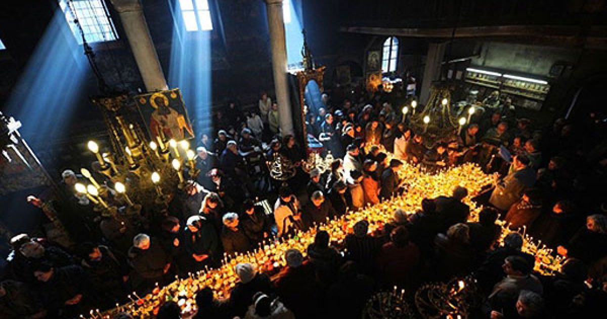 Болгарія, Благоєвград. Віруючі моляться поблизу хреста, викладеного зі свічок, які встановили на банки меду у церкві Пресвятої Діви в місті Благоєвград. У Болгарії пройшли святкування на честь святого Харлампія, захисника бджолярів. / © AFP