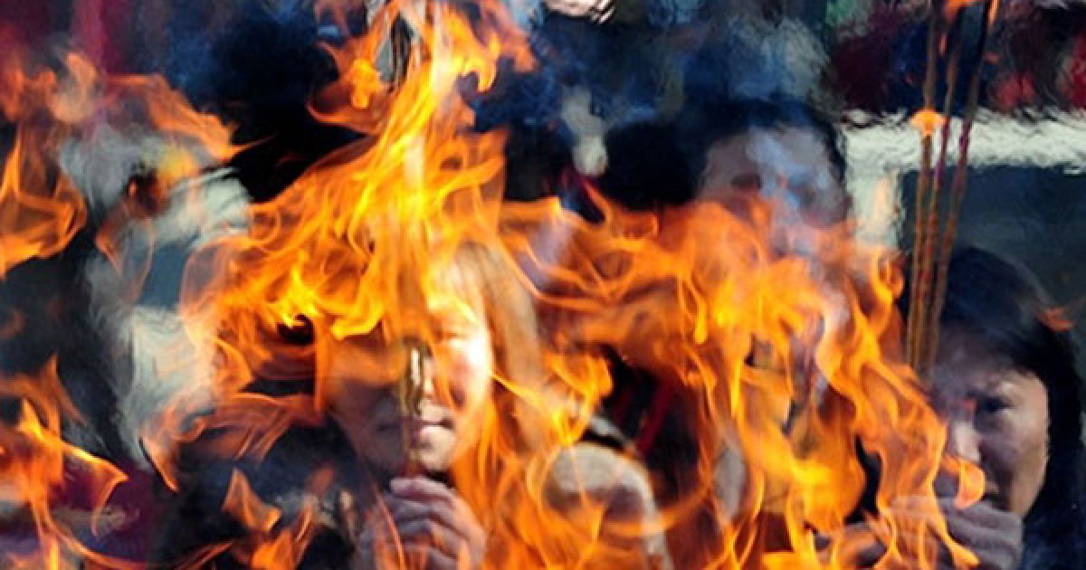 Китай, Пекін. Люди запалюють ароматичні свічки під час молитви у даоському храмі у Пекіні в перший день Нового року за місячним календарем. / © AFP