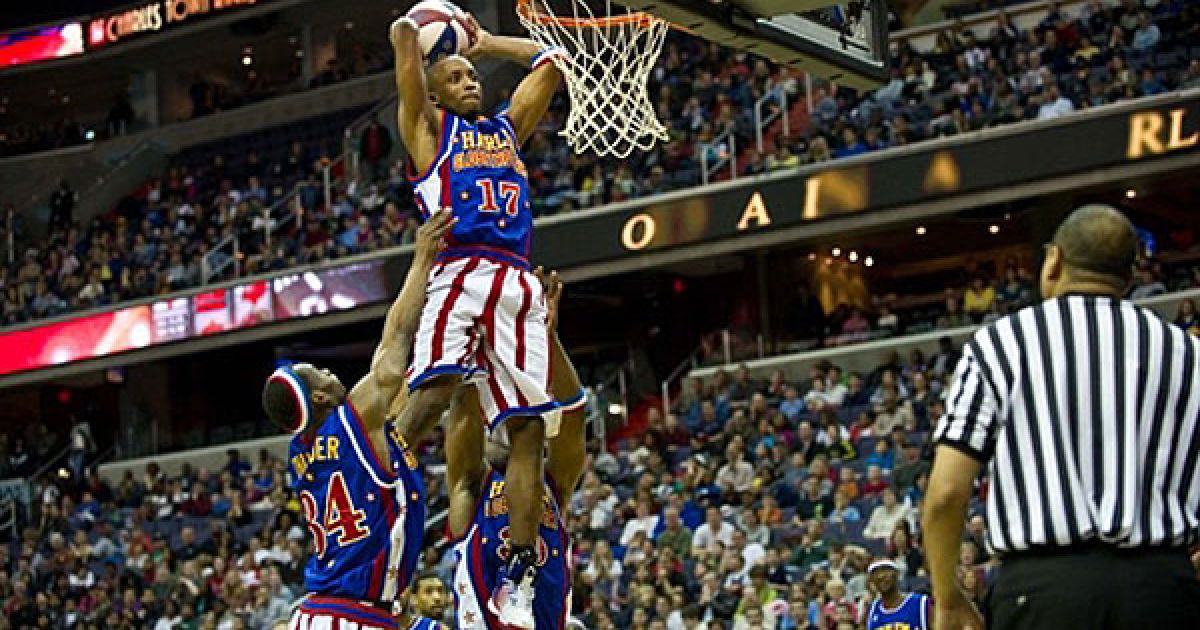 США, Вашингтон. Гравці "Harlem Globetrotters" Сандер Петвей і Сардж Джонсон піднімають свого товариша Рокета Ріверса до кошика під час гри проти "Washington Generals", яка відбулась у центрі "Верізон" у Вашингтоні. / © AFP