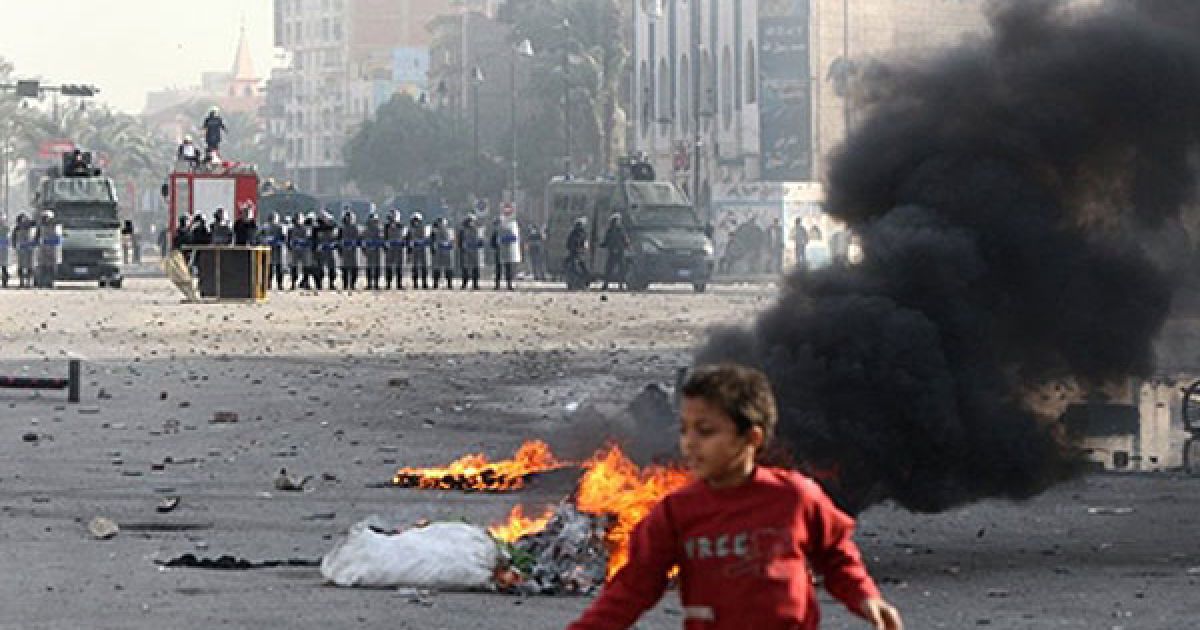 Єгипет, Суец. Дитина пробігає повз палаючі шини, доки поліцейські розганяють демонстрантів під час акції протесту в місті Суец. / © AFP