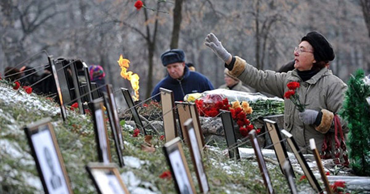 Україна, Київ. Жінка кидає квіти на пам&rsquo;ятник жертвам Чорнобильської трагедії. На меморіалі встановлені фотографії ліквідаторів і людей, які загинули, допомагаючи зупинити аварію на Чорнобильській АЕС 24 роки тому. В Україні провели церемонію пам&#039;яті ліквідаторів Чорнобильської трагедії. / © AFP