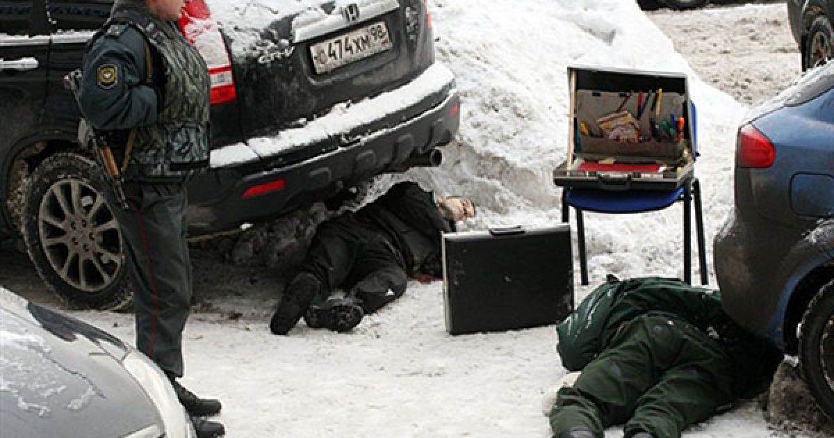 Росія, Санкт-Петербург. Міліціонер дивиться на тіла двох охоронців, убитих під час пограбування у Санкт-Петербурзі. Інкасатори і випадковий перехожий, що вигулював собаку неподалік, були вбиті кулями під час спроби пограбування банку. / © AFP