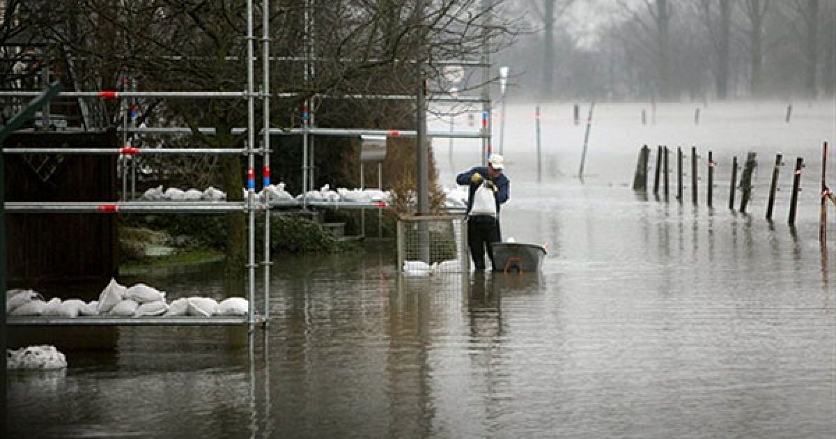 Людина складає мішки з піском перед своїм будинком, затопленим річкою Рейн у Кельні, Західна Німеччина. / © AFP