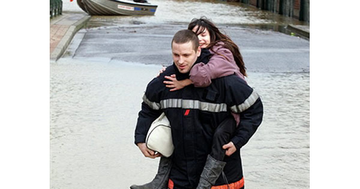 Пожежний несе дівчину під час евакуації мешканців селища Орина-Сент-Бенуа після розливу річки Уаза. / © AFP