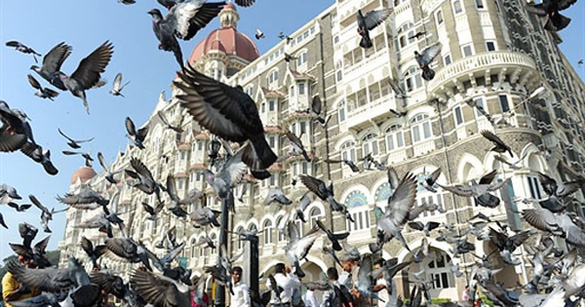 Індія, Мумбаї. Туристи годують голубів біля Воріт Індії поблизу готелю "Тадж-Махал Палас" у Мумбаї. / © AFP