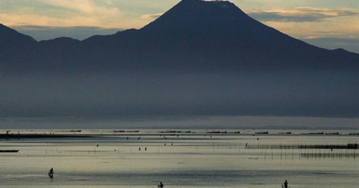 Філіппіни, Сорсогон. Рибалки стоять у воді поблизу вулкана Булусан у провінції Сорсогон. Десятки людей були змушені залишити свої будинки після пробудження філіппінського вулкана, який викинув стовп попелу у повітря 21 листопада. / © AFP