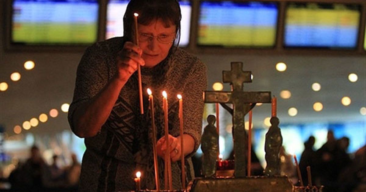 Росія, аеропорт Домодєдово. Жінка встановлює свічку під час панахиди в пам'ять про жертв вибуху у московському аеропорту Домодєдово. Терорист-смертник здійснив вибух у найбільшому аеропорті Росії, в результаті якого загинуло 35 людей. У Москві був оголошений день жалоби за загиблими. / © AFP