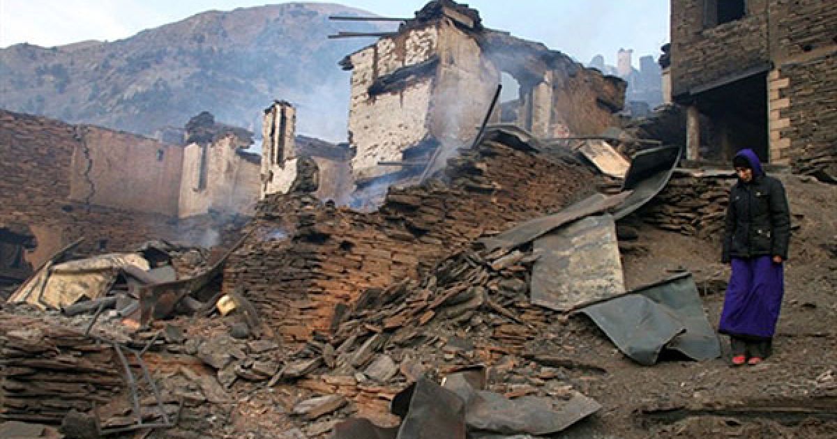 Росія, Цунті. Жінка стоїть біля одного з будинків, знищеного вогнем під час пожежі у віддаленому гірському селі Цибарі, у дагестанському районі Цунті. Під час пожежі було знищено близько 80 житлових будинків. / © AFP