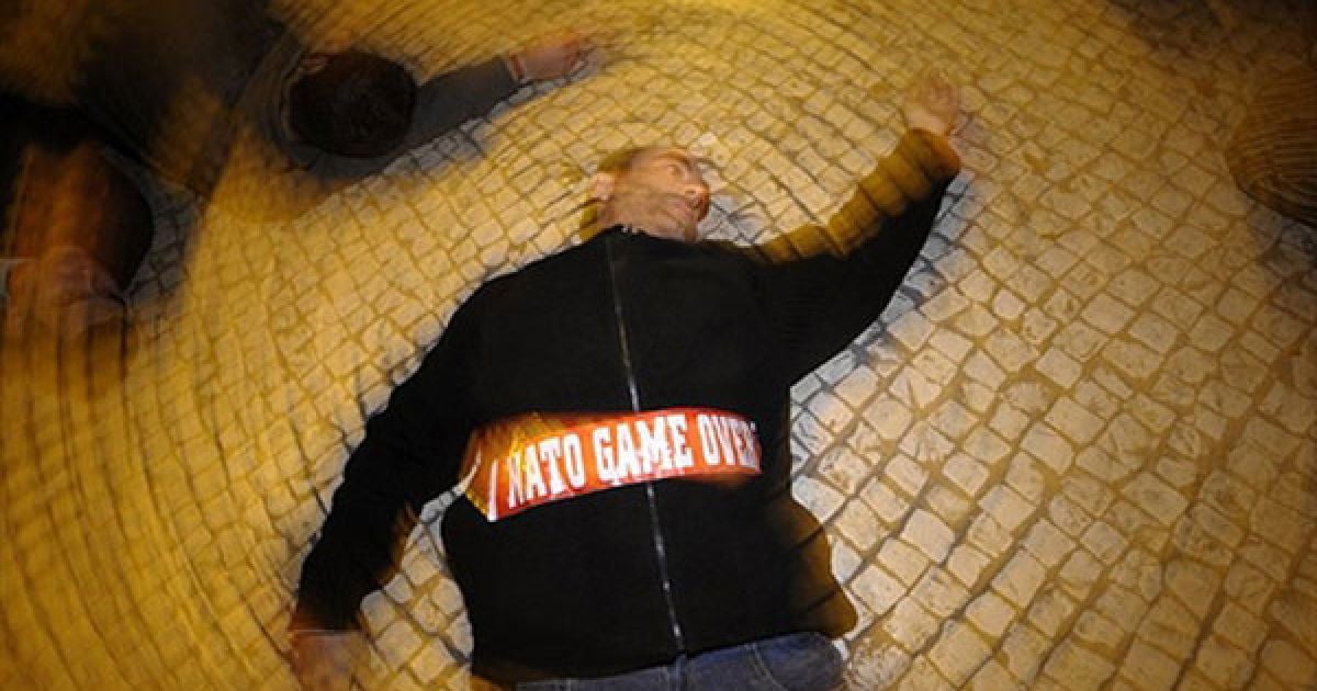 Португалія, Лісабон. Демонстрант лежить на землі під час акції протесту проти НАТО, яку провели в центрі Лісабона, де проходить саміт країн-членів НАТО. / © AFP