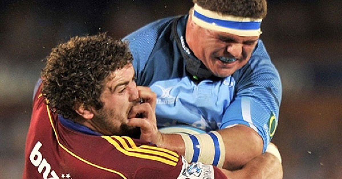 ПАР, Преторія. Гравець південноафриканської команди Bulls Вернер Крюгер атакує капітана новозеландської команди "Highlander" Джеймі Макінтоша під час матчу з регбі Super 15 на стадіоні Лофтус Версфелд у Преторії. / © AFP