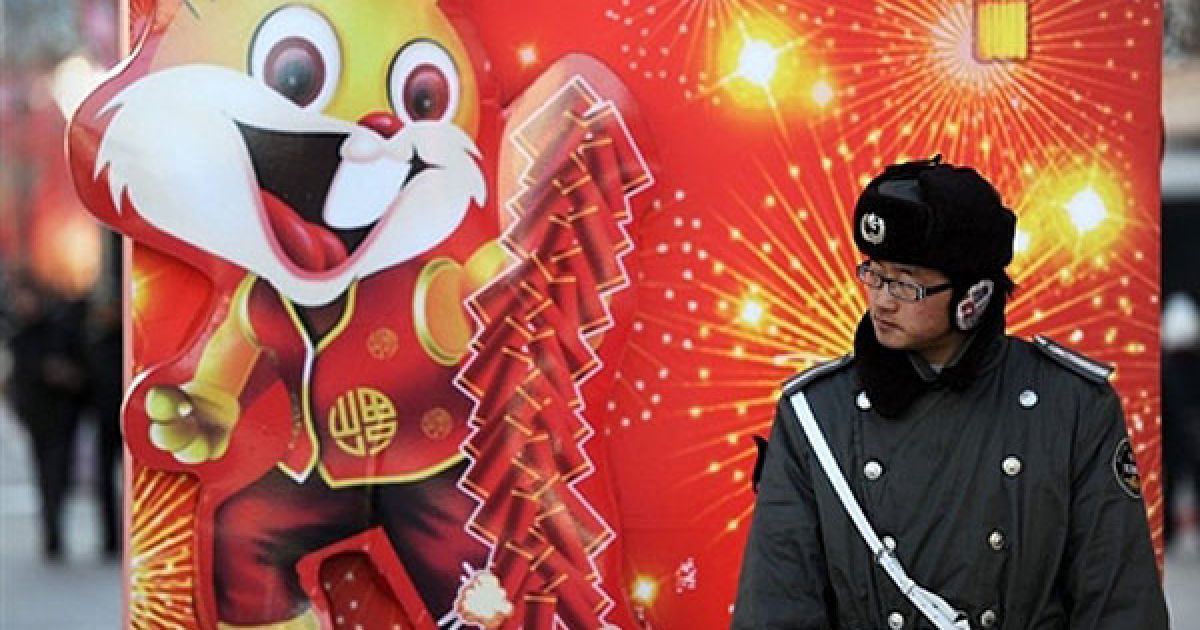 Китай, Пекін. Поліцейський стоїть на одній з торгових вулиць Пекіну, прикрашеній напередодні святкування місячного Нового року. Рік Кролика за китайським місячним календарем почнеться 3 лютого. / © AFP