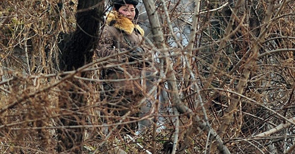 Китай, Даньдун. Озброєна північнокорейська жінка-військовий патрулює берег річки Ялу. / © AFP