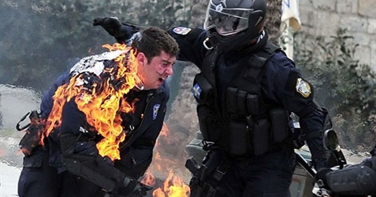 Греція, Афіни. Поліцейському, охопленому вогнем, допомагають його товариші під час зіткнень з демонстрантами у центрі Афін. Поліція застосувала сльозогінний газ поблизу грецького парламенту, коли почалися зіткнення з протестуючими, що кидали у поліцейських каміння і пляшки із запальною сумішшю. / © AFP