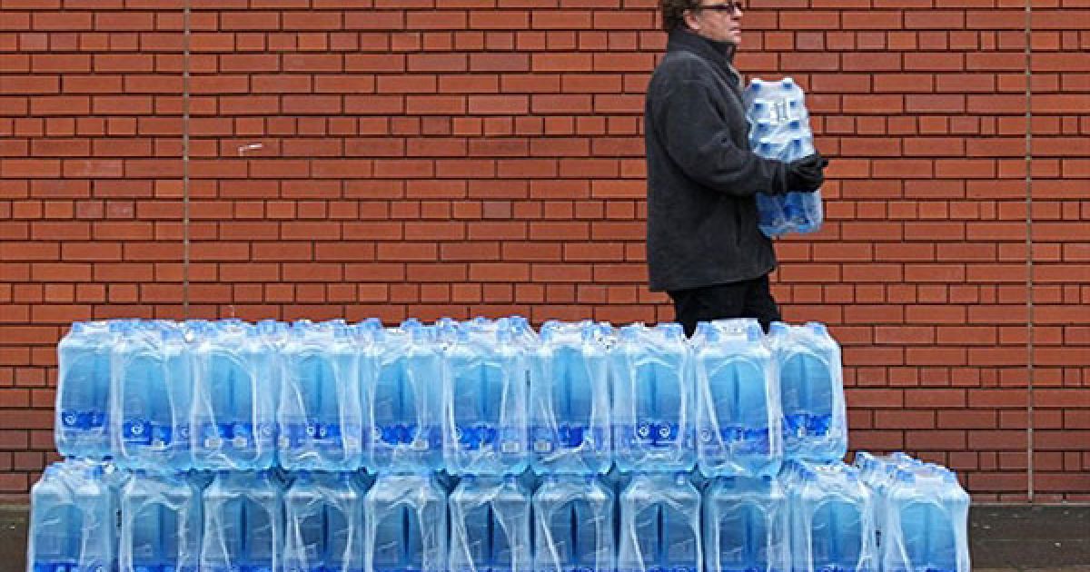 Великобританія, Белфаст. Чоловік забирає воду у пляшках, яку безкоштовно розповсюджує міська рада перед центром Олімпія у Белфасті, Північна Ірландія. Через комунальну аварію майже сорок тисяч людей залишилися без води і каналізації. Водопровідні труби луснули під час сильних морозів, десятки тисяч людей залишились без води більше ніж на тиждень. / © AFP