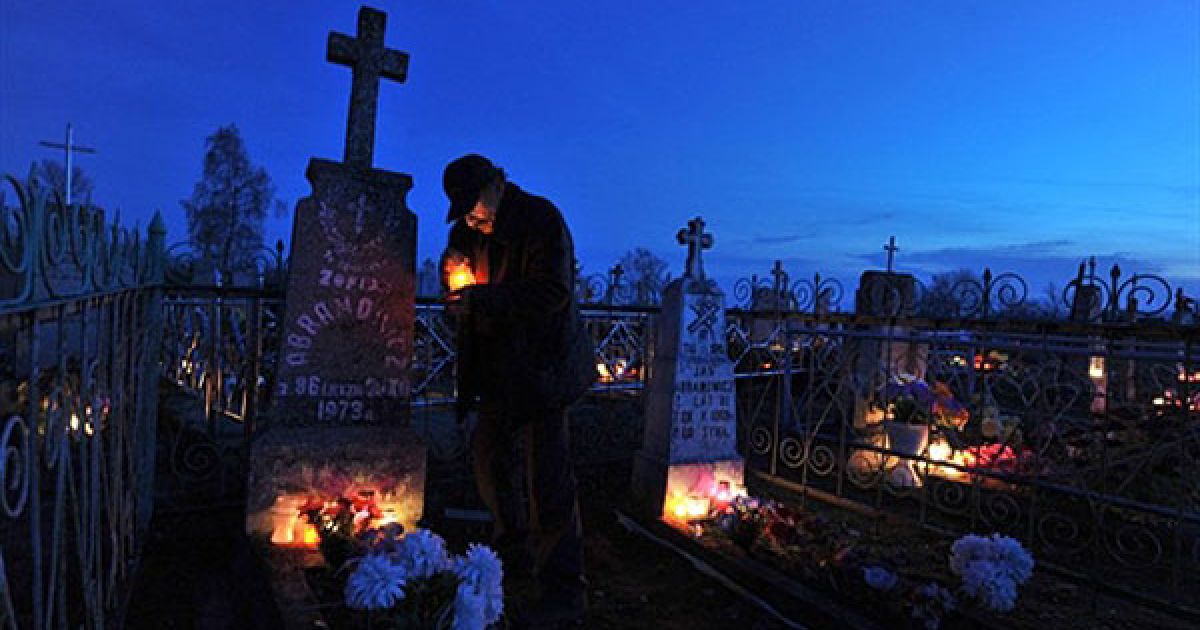 Білорусь, Борунов. Чоловік ставить свічки на могилу на цвинтарі біля білоруського села Борунов на честь свята Дзяди (Дня пам&#039;яті). / © AFP