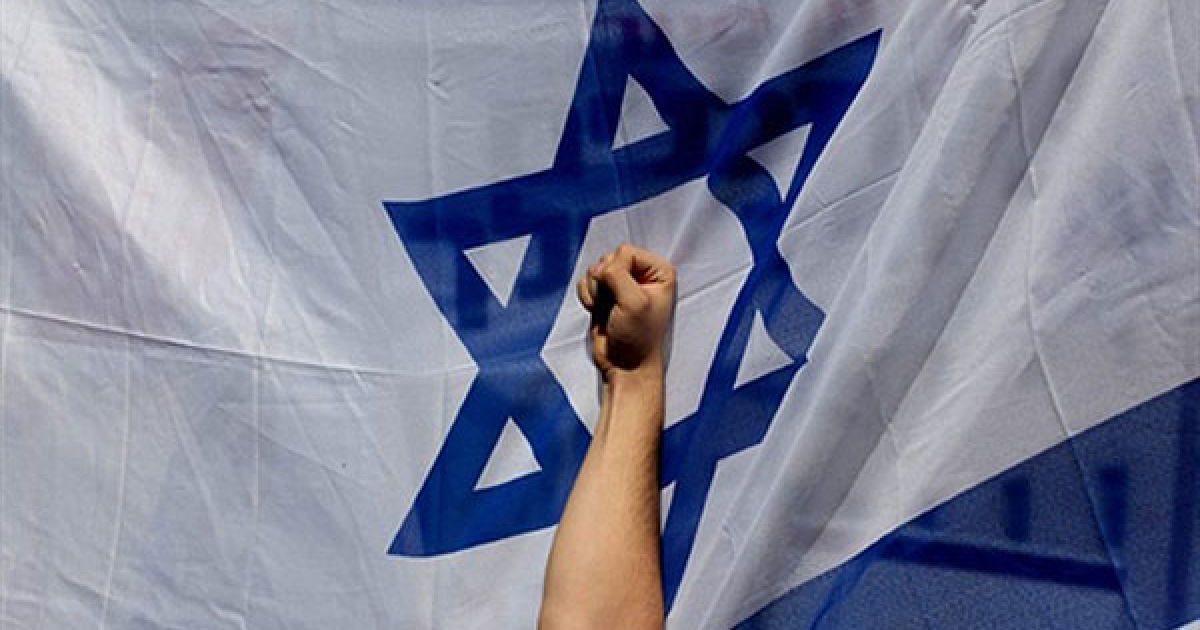 Єрусалим. Кулак учасника акції протесту на тлі ізраїльського прапору. Тисячі ізраїльських поселенців, в основному школярі, провели акцію протесту перед будівлею уряду в Єрусалимі з вимогами заморозити втілення плану врегулювання конфлікту. / © AFP