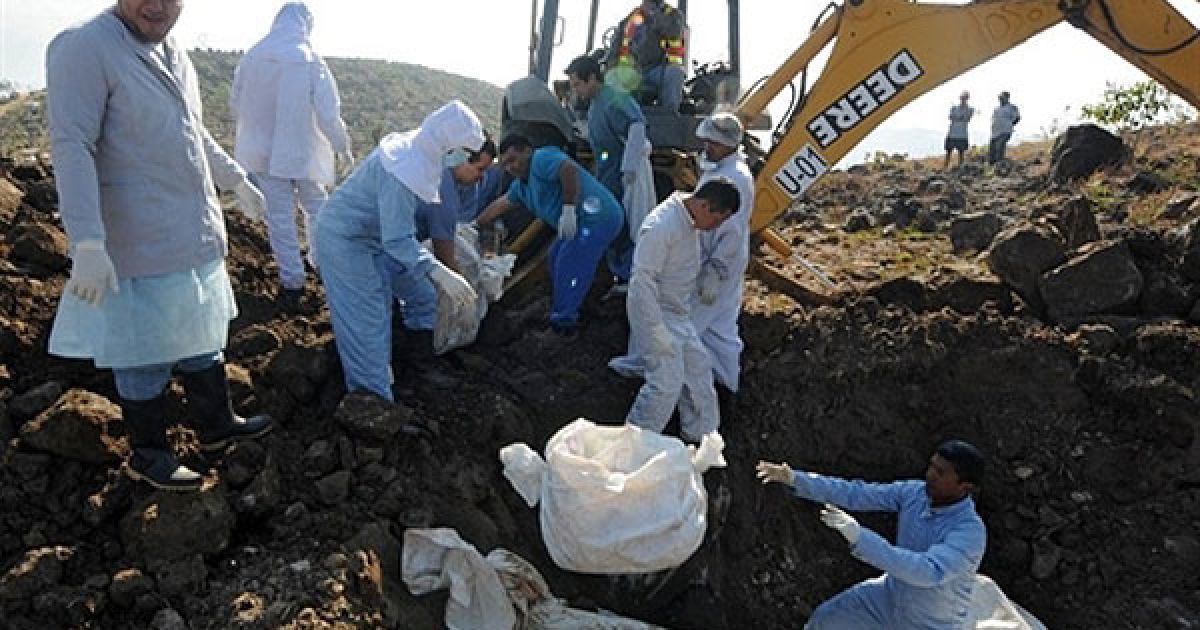 Гондурас, Тегусігальпа. Працівники моргу прокуратури Гондурасу ховають трупи у братській могилі на околиці міста Тегусігальпа. Тіла 22 непізнаних жертв насильства, знайдені у Тегусігальпі, були поховані у братській могилі. Щодня близько 20 людей гине у Гондурасі від насильства. / © AFP