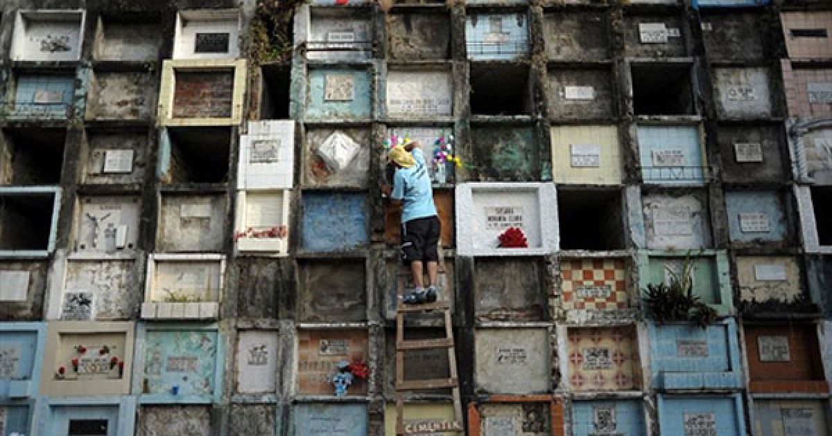 Сальвадор, Сан-Сальвадор. Людина кладе квіти на стіну гробниці на центральному кладовищі у місті Сан-Сальвадор на честь Дня мертвих. / © AFP
