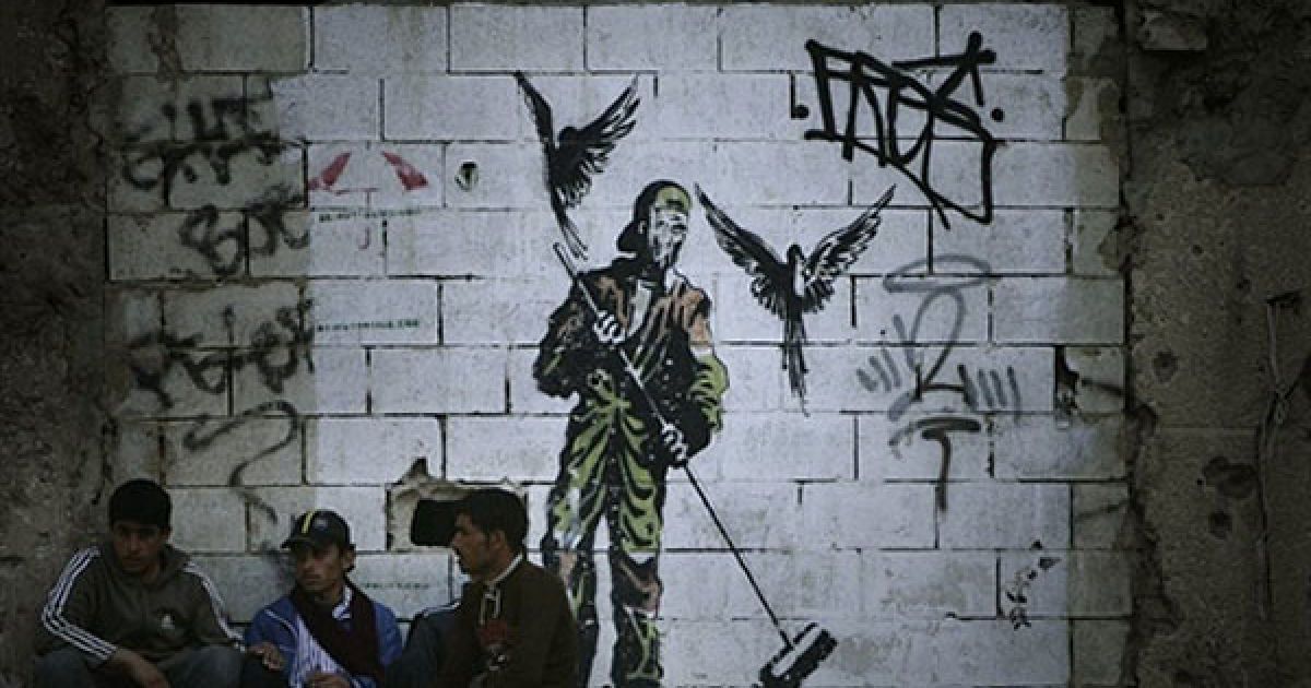 Ліван, Бейрут. Поденні працівники сидять під стіною, на яку нанесено малюнок із зображенням двірника у Бейруті. / © AFP