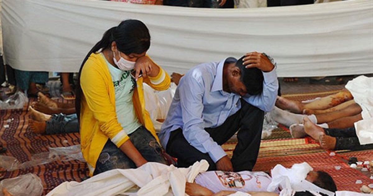 Камбоджа, Пномпень. Люди сумують, сидячи поруч із тілом свого молодшого брата, який загинув під час трагедії, що сталась у Пномпені під час святкування фестивалю води. Більше 350 людей загинули, сотні людей отримали травми у тисняві, яка виникла на вузькому мосту, де зібрались тисячі людей. / © AFP