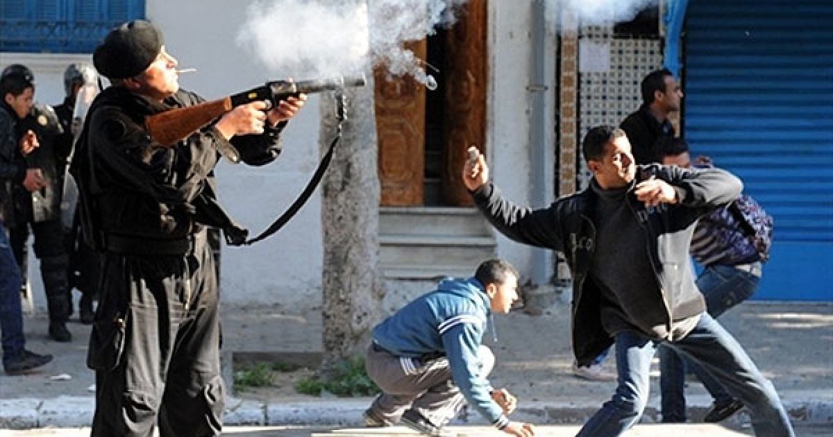 Туніс. Житель Туніса кидає каміння, а поліцейський стріляє сльозоточивим газом у мешканців центрально-туніського регіону Сіді-Бузід під час демонстрації перед офісом прем'єр-міністра Мохаммеда Ганнуші в Тунісі. ОМОН застосував сльозоточивий газ для розгону демонстрантів, що виступили проти тимчасового уряду країни. / © AFP