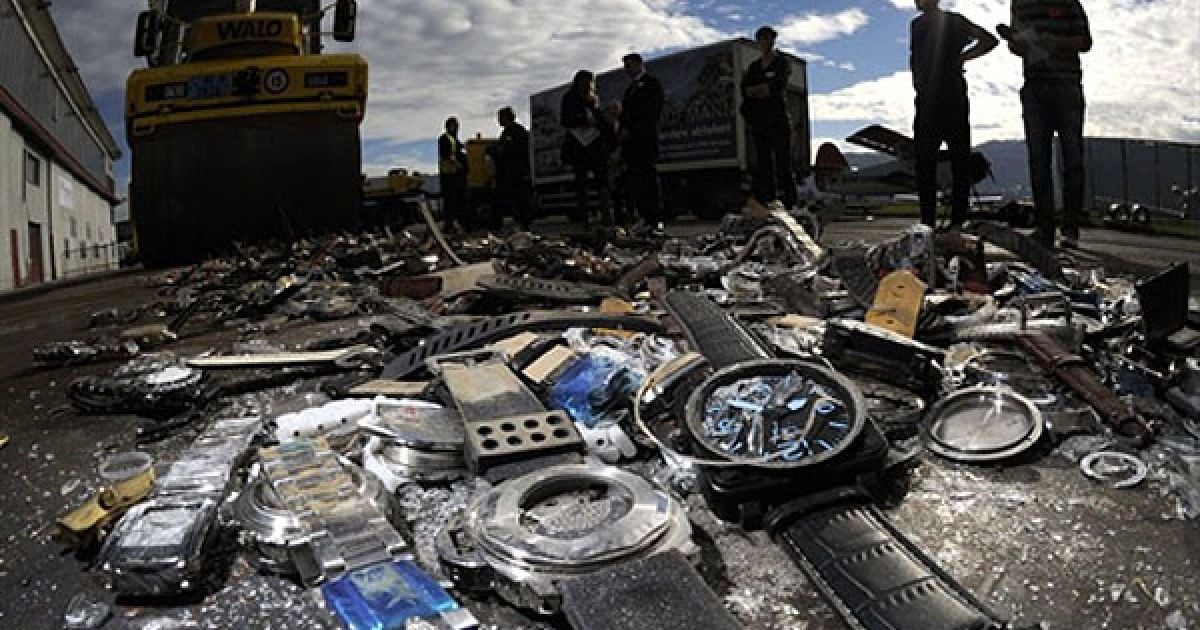 Швейцарія, Белп. Журналісти дивляться на процедуру знищення підроблених годинників і товарів, які розчавлює шляховий каток, під час запуску нової кампанії швейцарської організації по боротьбі з контрафактною продукцією та піратством "Зупинимо піратство". Підраховано, що швейцарська економіка щороку зазнає до 146 400 000 євро збитків через контрафактну продукцію та піратство. / © AFP