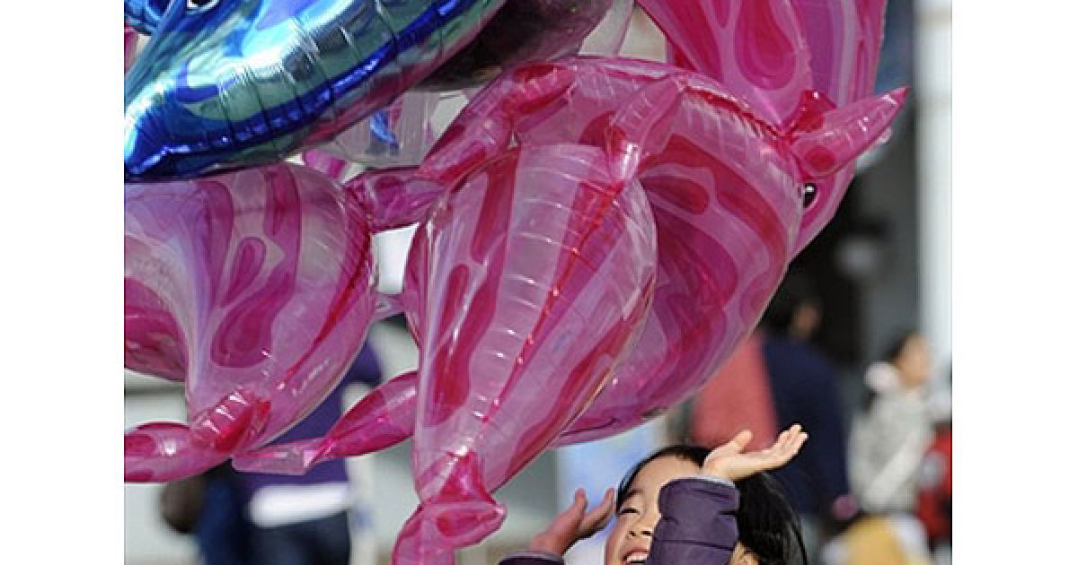 Японія, Йокогама. Дівчина грає з повітряною кулькою у формі дельфіна на площі у Йокогамі. / © AFP