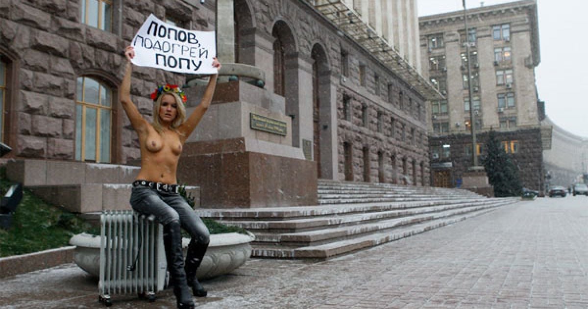 У 10-градусний мороз представниця FEMEN роздяглася по пояс і розгорнула плакат, адресований градоначальнику Києва Олександру Попову: "Попов, підігрій попу!". З собою під мерію активістки принесли електрообігрівач. / © Жіночий рух FEMEN