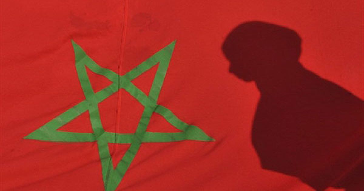 Марокко, Рабат. Тінь молодої жінки відбивається на марокканському прапорі під час демонстрації у Рабаті, яку провели на честь 35-річчя "Зеленого маршу". У листопаді 1975 року марокканський король Хасан II закликав 350 тисяч марокканців, "озброєних" Кораном і національними прапорами, вирушити до кордону із Західною Сахарою, щоб підтримати незалежність колишньої іспанської колонії. Колишня іспанська колонія, Західна Сахара, була анексована Марокко у 1975 році. / © AFP