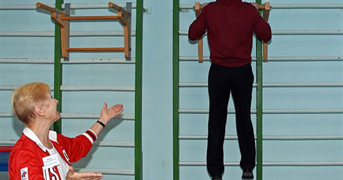 Росія, Ізмайловка. Місцева вчителька гімнастики Людмила Фоміна спостерігає, як президент РФ Дмитро Мєдвєдєв робить підтягування у спортивному залі під час візиту до середньої школи в селі Ізмайловка. / © AFP