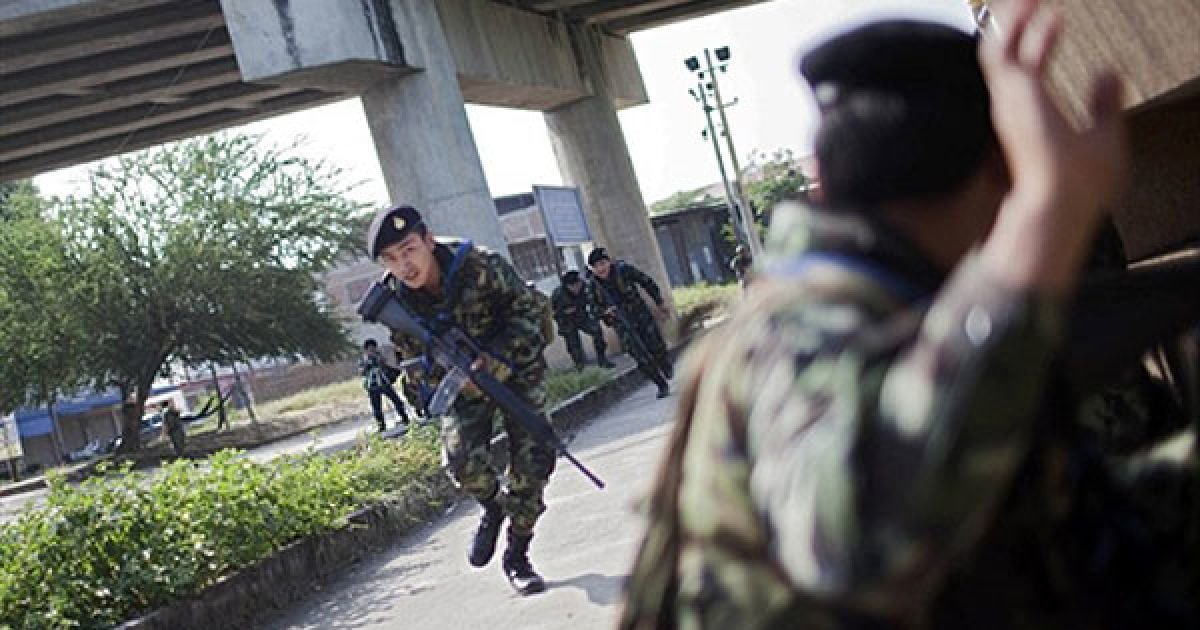 Таїланд, Мей Сот. Тайський солдат поспішає прикрити свого товариша під час зіткнення на тайсько-мьянмарському кордоні. Повстанці атакували урядові війська після виборів, в результаті чого троє цивільних осіб загинули, тисячі змушені були тікати через кордон з Таїландом. / © AFP