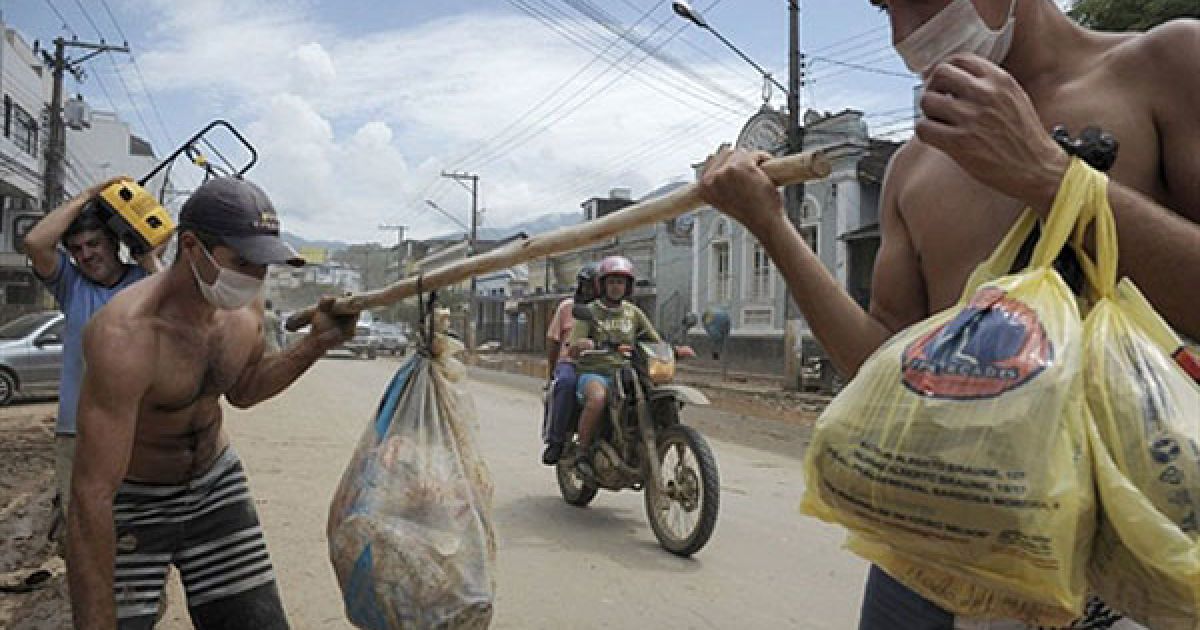 Бразилія, Нова-Фрібург. Місцеві мешканці, одягнені у захисні маски через жахливий сморід, намагаються врятувати речі з будинків, які серйозно постраждали під час руйнівних повеней у місті Нова-Фрібург, штат Ріо-де-Жанейро. Число загиблих від руйнівних повеней та зсувів у Бразилії досягло 640 осіб. / © AFP