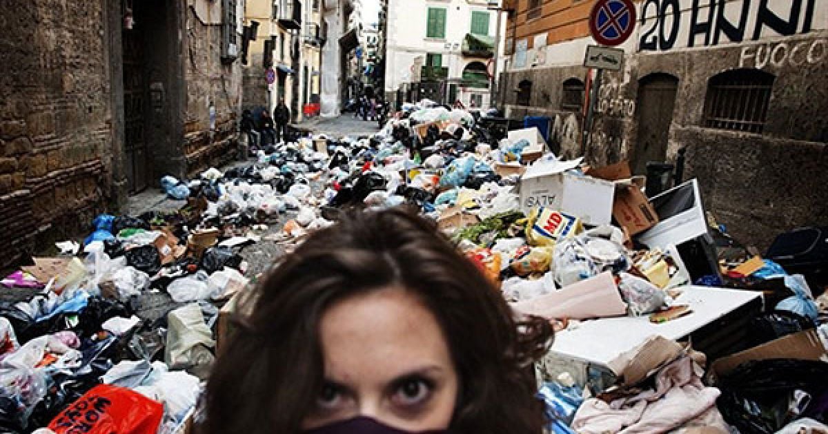 Італія, Неаполь. Жінка прикриває обличчя, доки вона йде вулицею, заваленою незібраним сміттям, у історичному районі міста Неаполь. Смердючі купи сміття накопичуються на вулицях Неаполя, наразі загальний обсяг незібраних відходів у місті досягає 3600 тонн. / © AFP