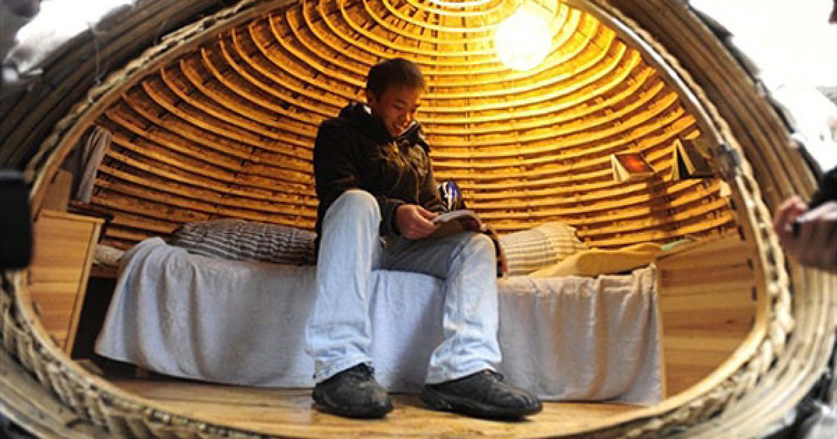 Китай, Пекін. 24-річний Дай Хайфей з китайської провінції Хунань лежить у своєму яйцеподібному мобільному будинку, в якому він мешкає упродовж останніх двох місяців неподалік від свого офісу в Пекіні. Сконструювати подібний будинок самостійно коштує близько 1000 доларів США. Він зроблений зі смуг бамбука і матраца, вкритого шаром водостійкого матеріалу, який також зберігає тепло. Назовні будинок вкрито мішками з тирсою і насінням трави, яка проростатиме навесні. / © AFP
