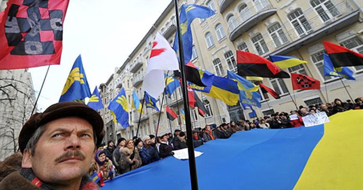 Україна, Київ. Чоловік стоїть під українським прапором під час мітингу, який зібрали представники націоналістичних партій перед будівлею Адміністрації президента України Віктора Януковича у Києві. Протестуючі вимагали покласти край політичним репресіям щодо опозиції, які почалися з початку президентства Януковича. / © AFP