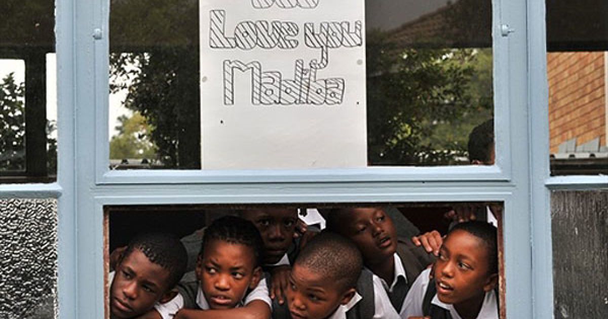 ПАР, Йоганнесбург. Школяри виглядають з вікна лікарні Мілпарк у Йоганнесбурзі, куди помістили колишнього президента Нельсона Манделу для проведення контрольних досліджень. Діти намалювали плакати із побажаннями здоров&rsquo;я 92-річному лауреату Нобелівської премії миру. Мадіба є клановим ім'ям, яким Манделу називають у країні. / © AFP