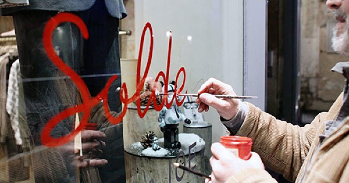 Франція, Париж. Людина малює слово "Soldes" ("Розпродаж") на вітрині магазину у Парижі напередодні першого дня розпродажів. / © AFP