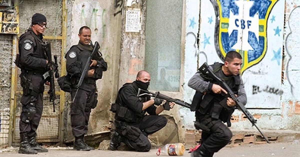 Бразилія, Ріо-де-Жанейро. Співробітник поліцейського спецпідрозділу рушає вперед, доки інші стоять біля входу до району нетрів Віла Крузейро у Ріо-де-Жанейро. Наркоторговці здійснили кілька нападів на поліцейські машини та підпалили їх у відповідь на проведення поліцейських операцій у деяких нетрях міста. Щонайменше 23 людини було вбито і 153 заарештовано протягом кількох днів зіткнень бразильських сил безпеки і банд наркоторговців. / © AFP