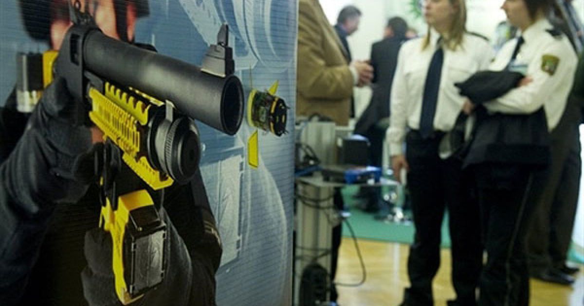 Німеччина, Берлін. Рекламний плакат кулемета Taser X-12, на який можуть встановлюватися електронні пристрої Taser XREP від виробника зброї "Мосберг", вивішено на стенді Taser під час Європейського поліцейського конгресу в Берліні. / © AFP