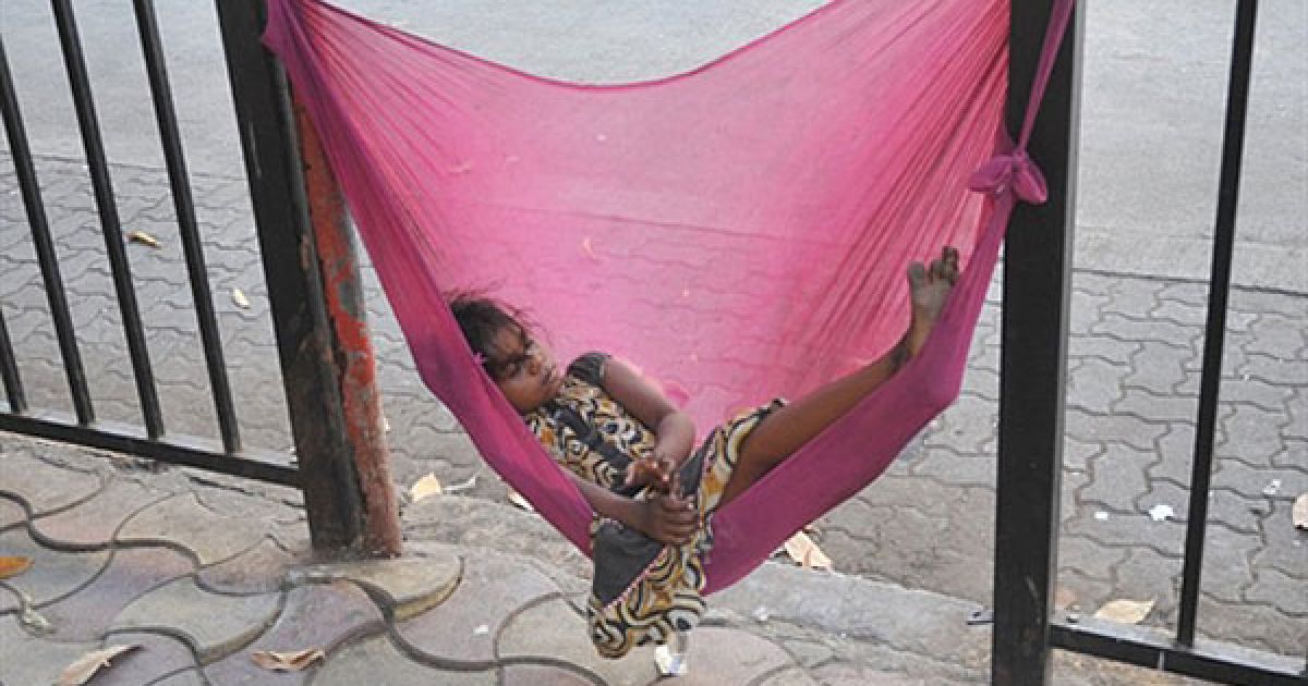 Індія, Мумбаї. Індійська безпритульна дівчинка відпочиває у гамаці на узбіччі дороги в місті Мумбаї. Безпритульні діти в Мумбаї позбавлені базової освіти, житла і послуг медичних установ. / © AFP