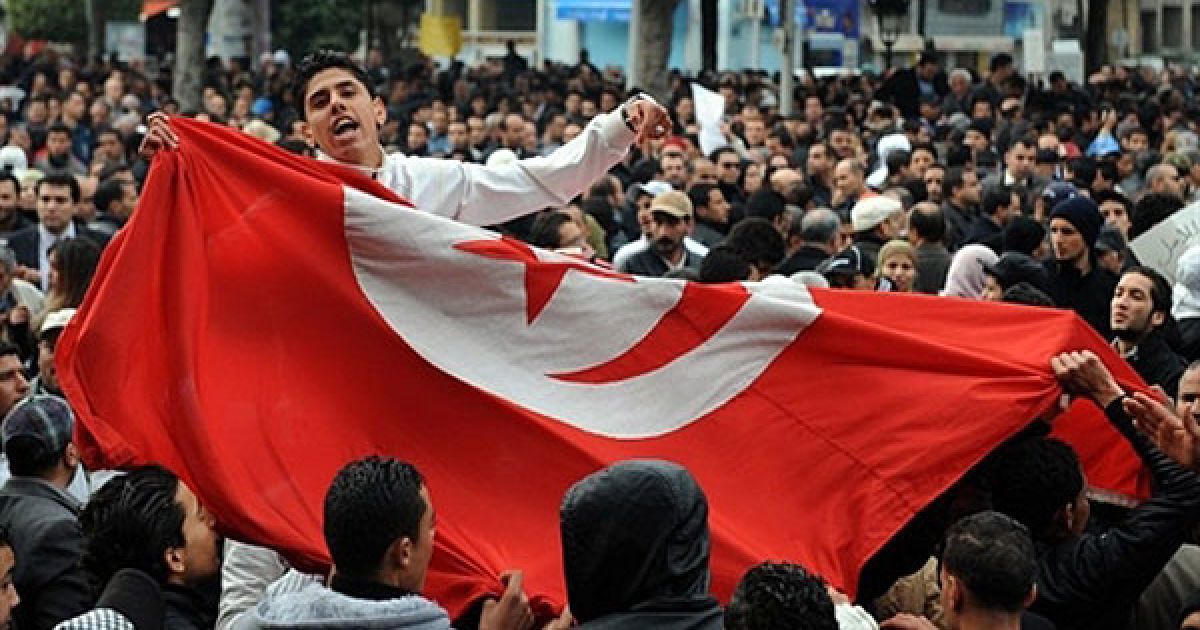 Туніс. Учасник акції протесту в Тунісі тримає національний прапор під час антиурядової демонстрації на проспекті Хабіб Бургиба. Сотні людей, які брали участь у першому мітингу на підтримку нового тимчасового уряду Тунісу, були розігнані іншими демонстрантами, що вимагали відставки уряду. / © AFP