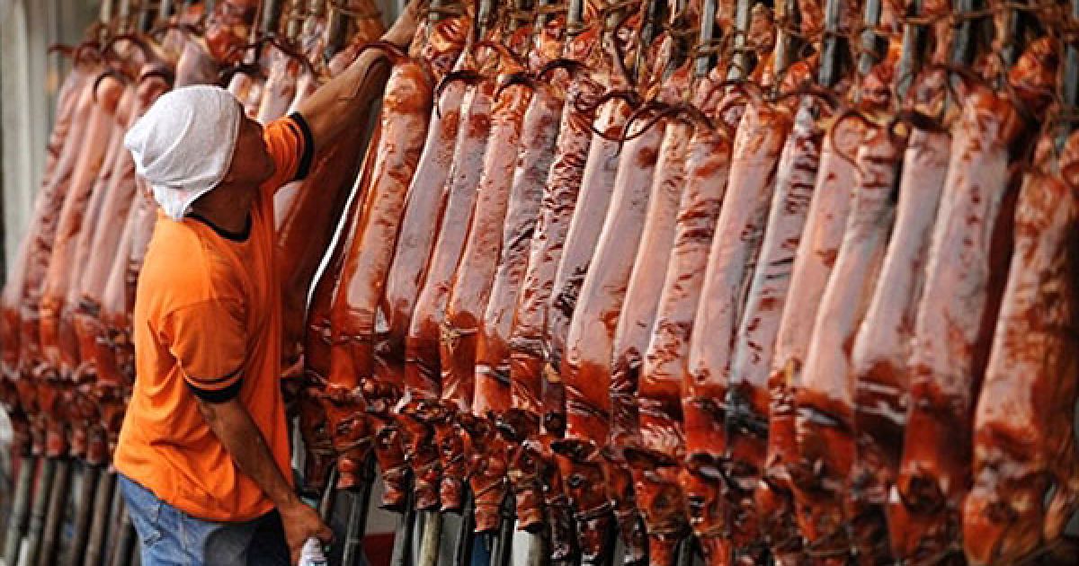 Філіппіни, Маніла. Працівник пересуває смажених поросят у магазині Маніли. "Lechon", або смажене порося, є традиційною складовою різдвяних і новорічних свят на Філіппінах. / © AFP