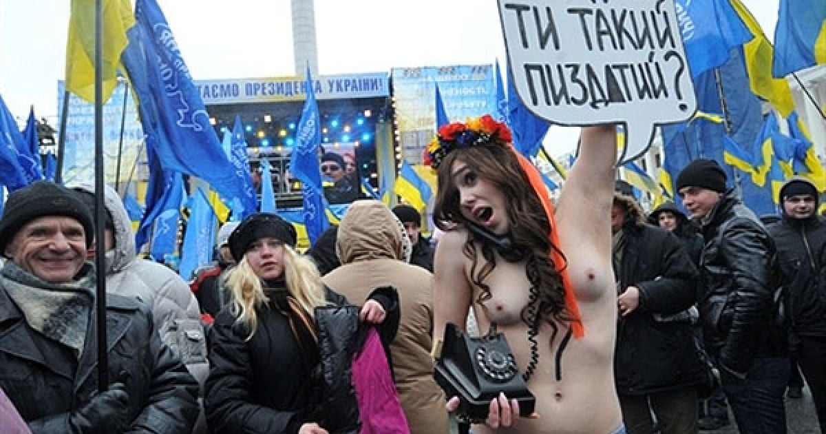 Україна, Київ. Оголена активістка жіночого руху FEMEN тримає плакат із непристойним питанням до президента Віктора Януковича на Майдані Незалежності в Києві. Президент Віктор Янукович поспілкувався в прямому ефірі з громадянами України в рамках телепроекту "Розмова з країною" на відзнаку першої річниці Януковича при владі. / © AFP
