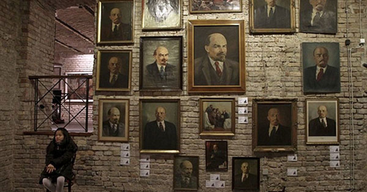 Угорщина, Будапешт. Дівчина сидить перед портретами колишнього радянського лідера Володимира Леніна. Більше 230 експонатів часів комуністичної епохи виставлені на аукціон, кошти від якого підуть жертвам затоплення червоним шламом, яке сталося минулого місяця в Угорщині. / © AFP