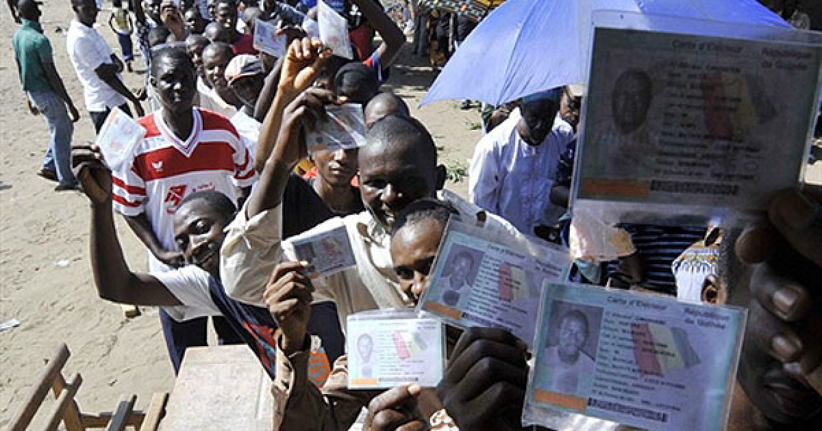 Кот-д'Івуар, Абіджан. Гвінейські жителі Кот-д'Івуара показують свої виборчі карти, доки вони стоять у черзі на виборчу дільницю в Абіджані. / © AFP